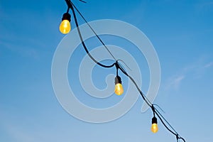 Light bulbs on string wire against sunset sky by the sea