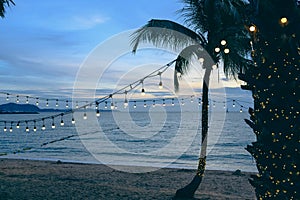 Light bulbs on string wire decoration at the party event festival on the beach at sunset. Outdoor holiday background. Copy space