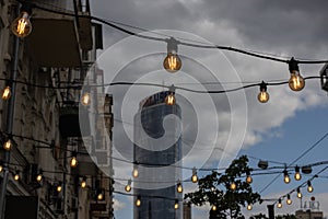 light bulbs on string wire hanging on poles against sunset sky