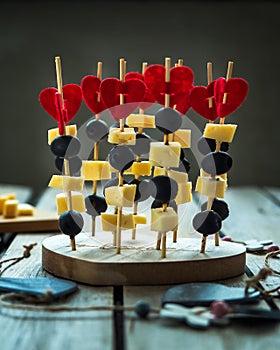 Light canapes for loved ones on Valentine`s Day, canapes and heart decor. The composition stands on an wooden table.
