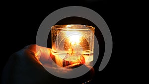 Light of a candle on glass bowl with Mother Mary picture in the hand in the dark. Christian catholic symbol of faith.