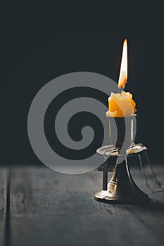 Light candle with holy bible and cross or crucifix on old wooden background in church.Candlelight and open book on vintage wood