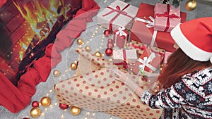 In the light of the Christmas tree, a woman carefully packs gifts in magic paper, adding a sense of warmth and