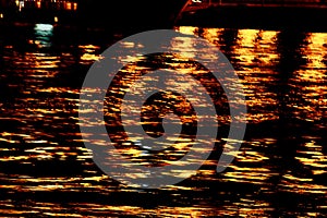 The light of city lanterns is reflected in the water at night. waves on the river