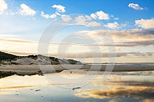 Light clouds reflected in shallow waters of a sandy beach. Beautiful sunset at Far North, New Zealand