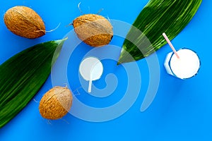 Light cocktail with coconut milk. White tropical beverage in glasses with straw on blue background with coconut and palm