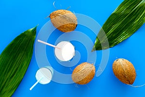 Light cocktail with coconut milk. White tropical beverage in glasses with straw on blue background with coconut and palm