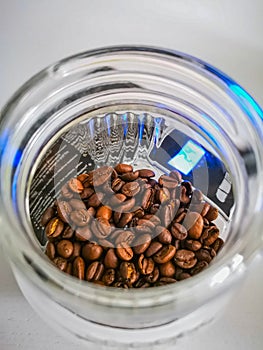 Light coffee beans in glassy cup standing on weight