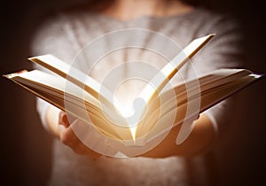 Light coming from book in woman's hands in gesture of giving