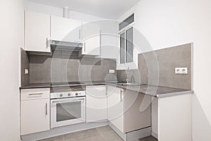 Light compact kitchen with stove, extractor hood and sink and window. Concept of kitchen in a small apartment. Modern