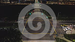 The light on the crossroad at night and movement of cars. Shot. Road intersection traffic at night in the center of the