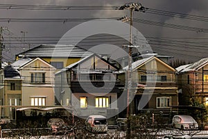 Light dusting of snow on suburban houses with lights on at night