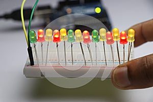 Light emitting diodes on breadboard with glowing lights controlled by micro controller board on background held in hand
