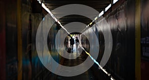 The Light at the End of the Tunnel. Young couple walking in a dark protective passage