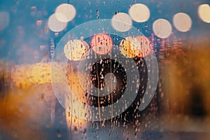 Light of evening city and rain drops on the window. Abstract blurred background