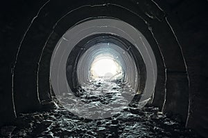 Light and exit in the end of dark long tunnel or corridor, way to freedom concept. Industrial round chalk mine passage