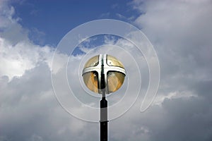 Light fixture against white clouds and blue sky