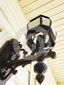 A light fixture hanging on the outside wall of the white house black metal