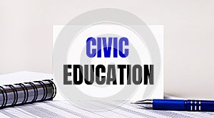 On a light gray background, a notebook, a blue pen and a sheet of paper with the text CIVIC EDUCATION. Business concept