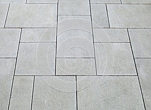 Light gray concrete outdoor pavement with tiles of different shapes.