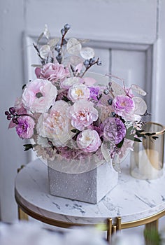 Light gray concrete planter with flowers. Gently pink anemones, pink roses and cream peonies with eucalyptus