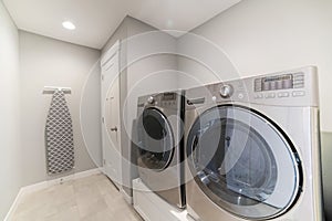 Light gray laundry room with tiles, washer, dryer and storage room