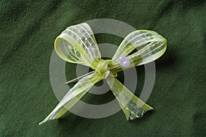 Light-green bow with two white pins and darkgreen background. Handmade concept - Image