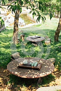 Light green ceramic tea set including jar, cups and plate on stone table under tree shadow at Ham Rong Mountain Park in Sa Pa