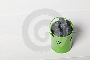 Light green decorative bucket with large blueberries. International day without diets. On a white background. Close-up