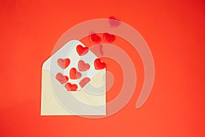 Light green envelope with red falling hearts on a red background. Happy Valentine's Day greeting, background