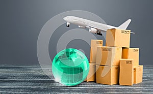 Light green globe near cardboard boxes and freight plane. International delivery of goods and products. Logistics, infrastructure