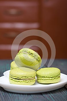 Light green macarons lie on a saucer. On pine planks with a crisp woody texture