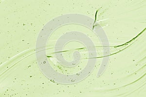 Light green serum texture. Aloe vera gel background. Clear colored liquid cream, face mask smear photo