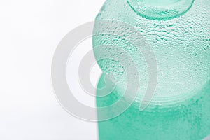 Light Green Sweated Frosty Bottle with Clear Pure Cool Water on White Background. Hydration Summer Refreshment