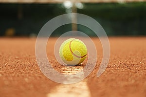 Light green tennis ball on clay court close up