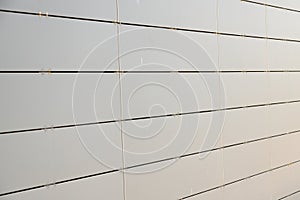 Light grey metal wall of a building made of small metal rightangled sheets