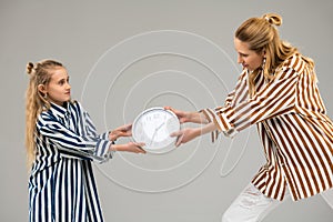 Light-haired resolute girls in striped shirts competing for usual white clock