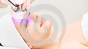 Light infrared therapy. Cosmetology head procedure. Beauty woman face. Cosmetic salon device. Facial skin rejuvenation