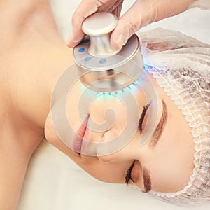 Light infrared therapy. Cosmetology head procedure. Beauty woman face. Cosmetic salon device. Facial skin rejuvenation