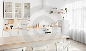 Light kitchen design with white wooden furniture and island, utensils and kitchenware on shelves, range hood