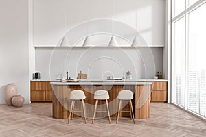 Light kitchen interior with island and seats, kitchenware and panoramic window