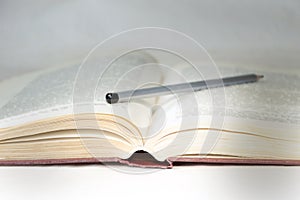 Light of knowledge is an open book close-up, illuminated by ray of light, with pencil on it. Concept of education, knowledge