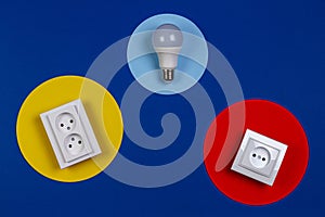 Light lamp bulb and electrical power sockets on geometrical yellow red and navy blue background