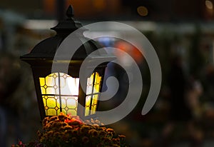 Light lantern street in the dark. Lamp with stained glass windows close-up on a blurred city background