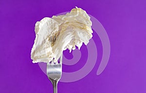 1 light lettuce leaf on a fork on a lilac