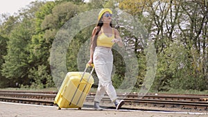 A light luggage suitcase sparkles on the railway platform, embodying the dreams and desires of a young woman to open new