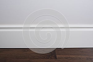 Light matte wall, white baseboard and tiles immitating hardwood flooring