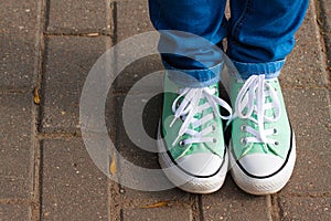 Light mint youth sneakers shod on legs in blue jeans