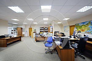 Light office with work desks, computers and map.