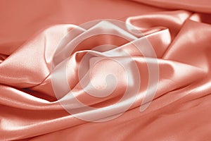 Light pale coral silk satin. Smooth fabric. Peach pink color. Elegant background. Drapery.